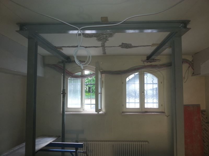 Ein Zimmer mit Himmelbett und zwei Fenstern