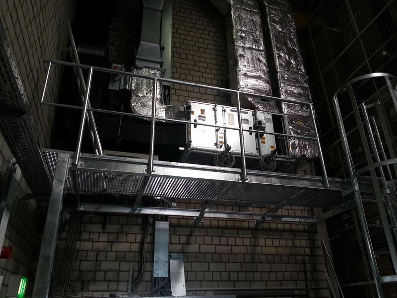 Eine Metallplattform mit Geländer und Treppen in einem Gebäude