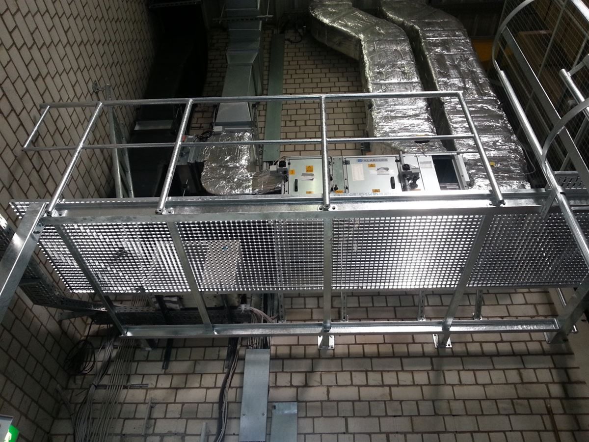 Eine Metalltreppe, die zu einer Backsteinmauer mit Metallgeländer hinaufführt.