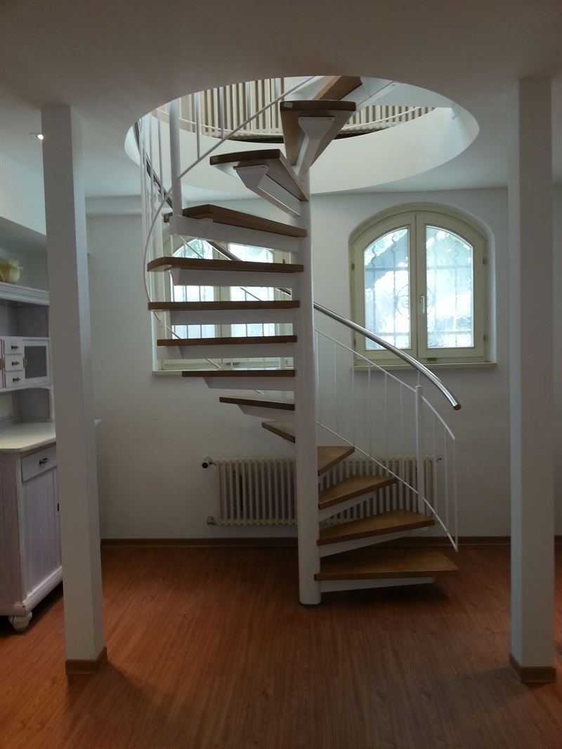 Eine Wendeltreppe mit Holzstufen und einem weißen Geländer