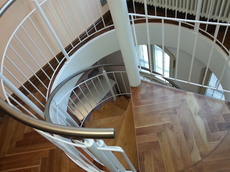 Eine Wendeltreppe mit weißem Geländer und Holzstufen