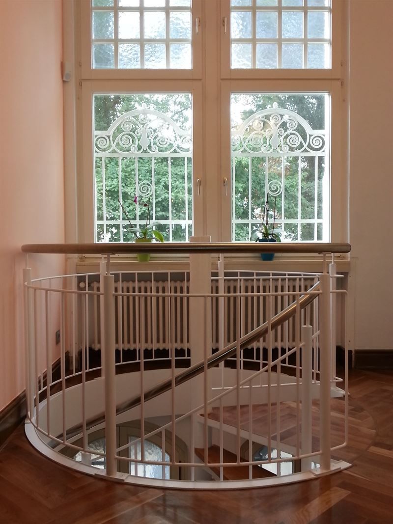 Eine Wendeltreppe mit einem weißen Geländer und einem Fenster