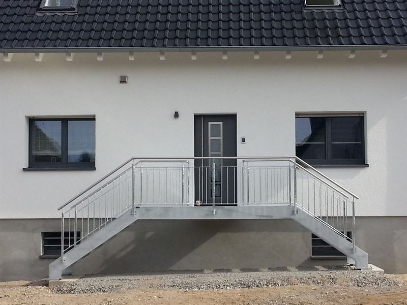 Ein weißes Haus mit einer Metalltreppe, die zur Haustür hinaufführt.