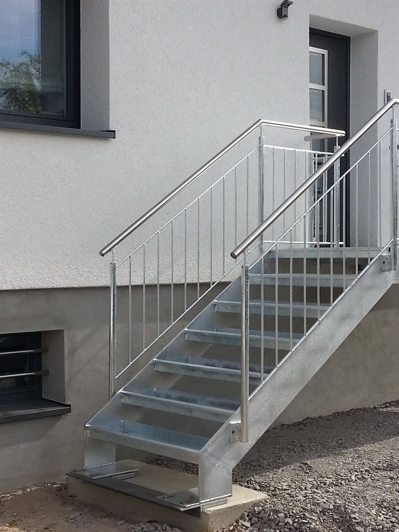 Eine Treppe mit einem Edelstahlgeländer an der Seite eines Gebäudes.