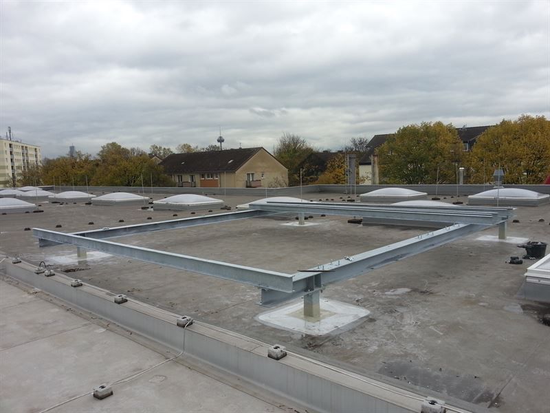 Auf einem Betondach sitzt ein Metallrahmen.