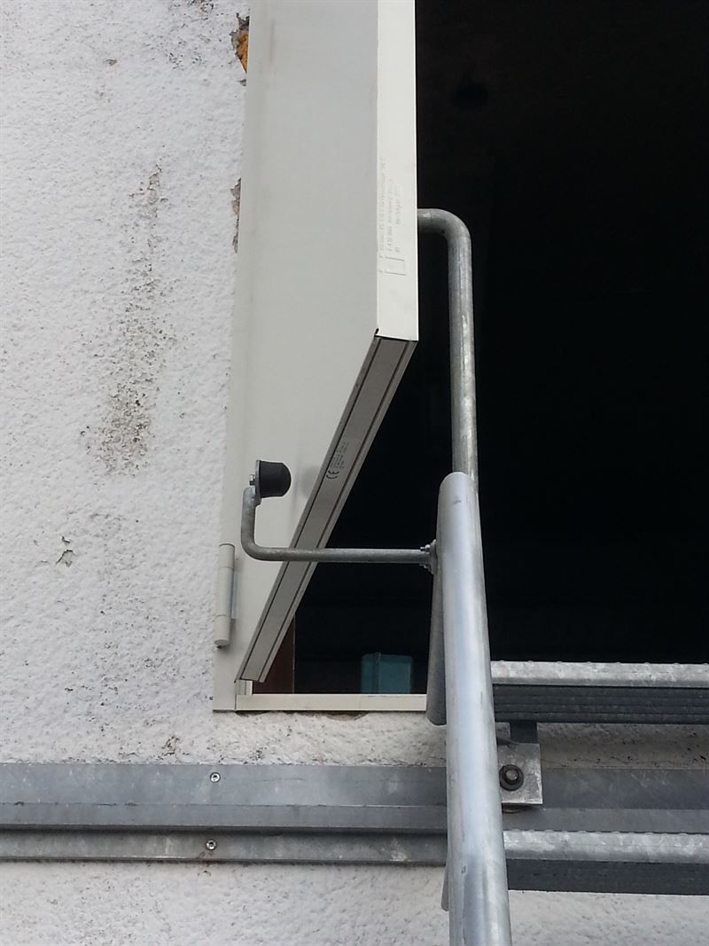 Eine weiße Tür mit einem Metallgeländer an der Seite eines Gebäudes.