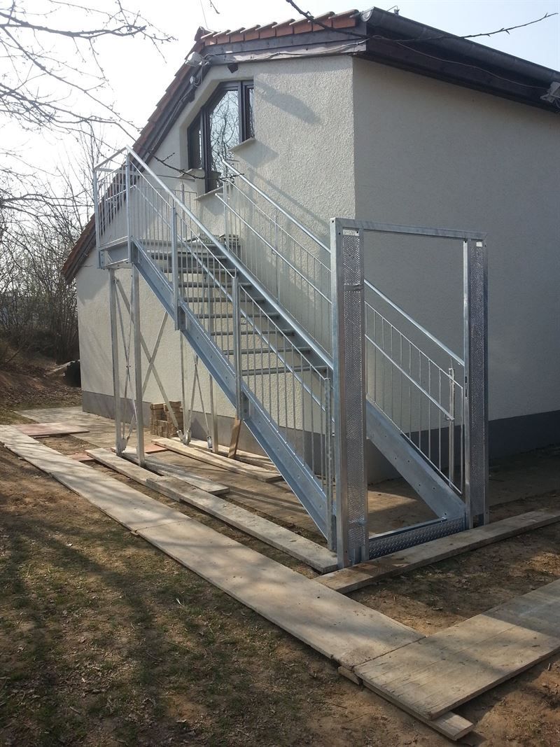 Eine Metalltreppe führt hinauf zu einem Haus.
