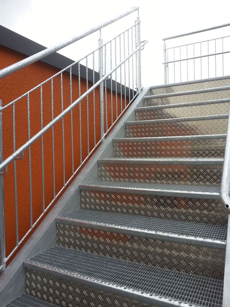Eine Treppe mit einem Metallgeländer, die zu einem Gebäude hinaufführt.