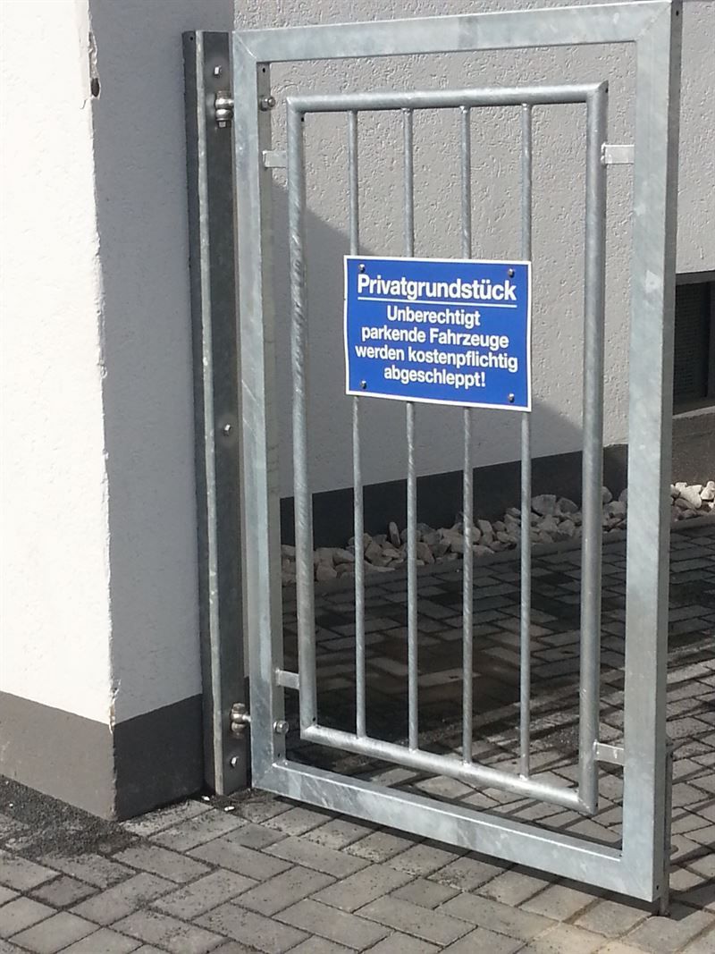 Ein Metalltor mit einem blauen Schild darauf.