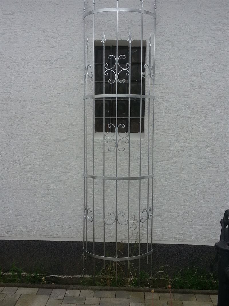 Vor einem weißen Gebäude steht ein Metallkäfig.