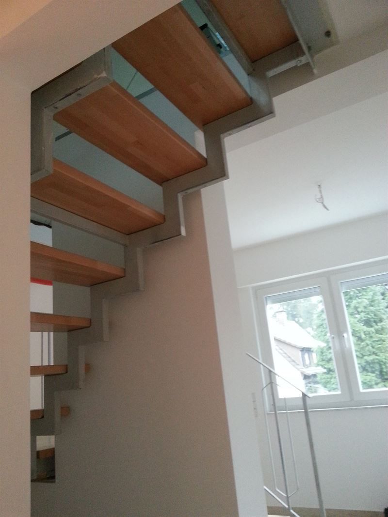 Eine Holztreppe in einem weißen Raum mit einem Fenster