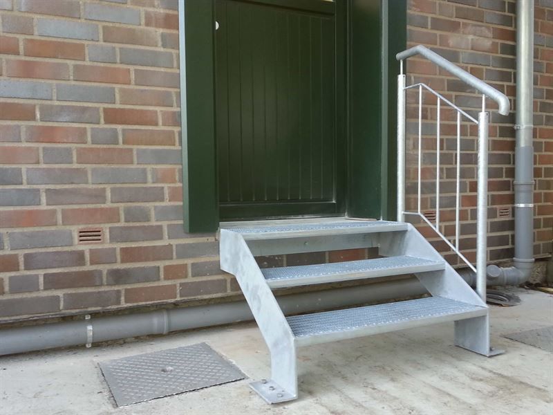 Eine Treppe, die zu einer Tür an einem Backsteingebäude führt