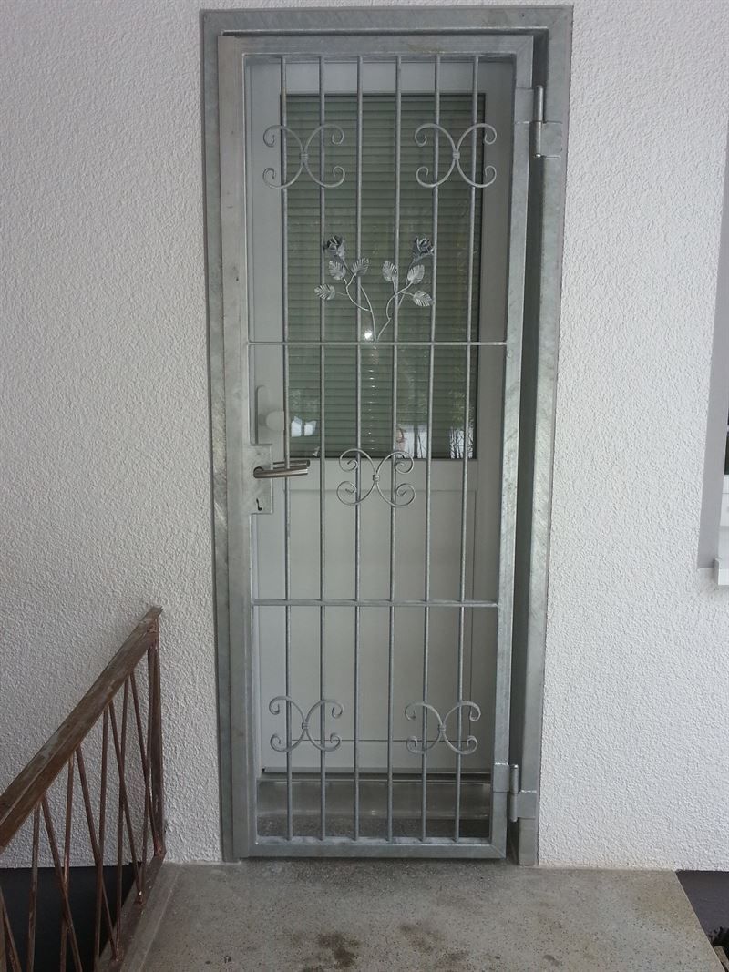 Eine weiße Tür mit einem schmiedeeisernen Tor darauf.