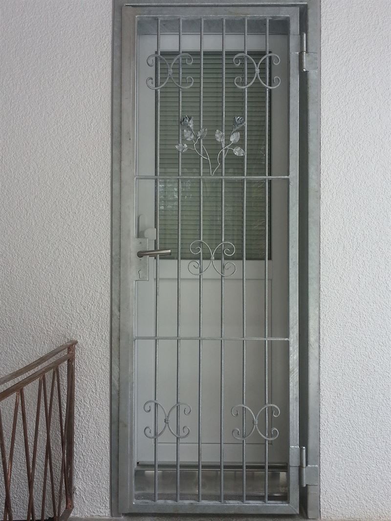 Eine weiße Tür mit einem schmiedeeisernen Tor darauf.