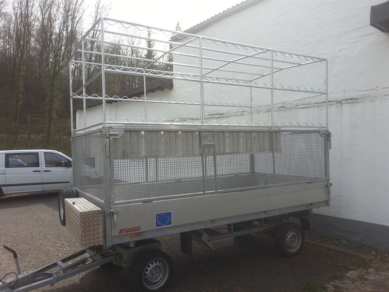 Vor einem Gebäude steht ein Anhänger mit Plane darauf.