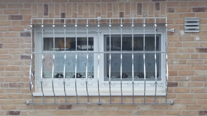 In einer Ziegelwand befindet sich ein Fenster mit einem Metallgitter.