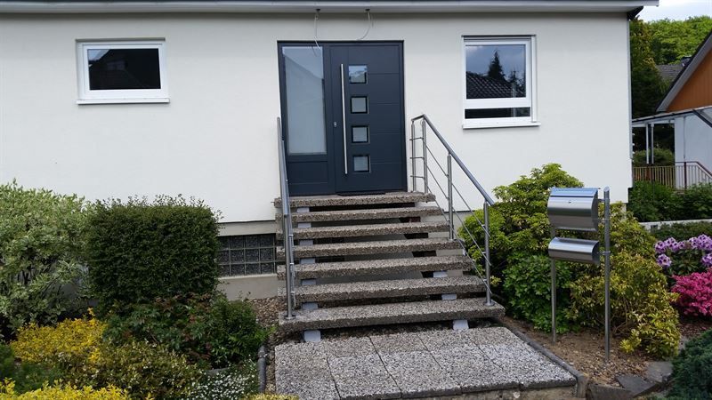 Ein weißes Haus mit einer Treppe, die zur Haustür hinaufführt.