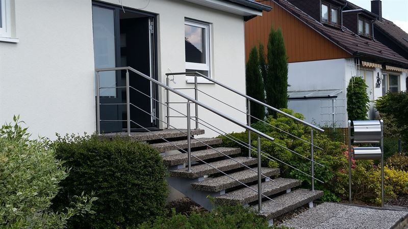 Ein weißes Haus mit Treppe und Edelstahlgeländer