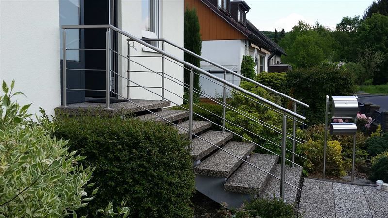 Eine Treppe mit Edelstahlgeländer und Briefkasten vor einem Haus.