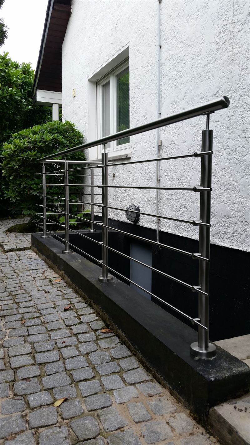 An der Seite eines Gebäudes wird ein Edelstahlgeländer angebracht.