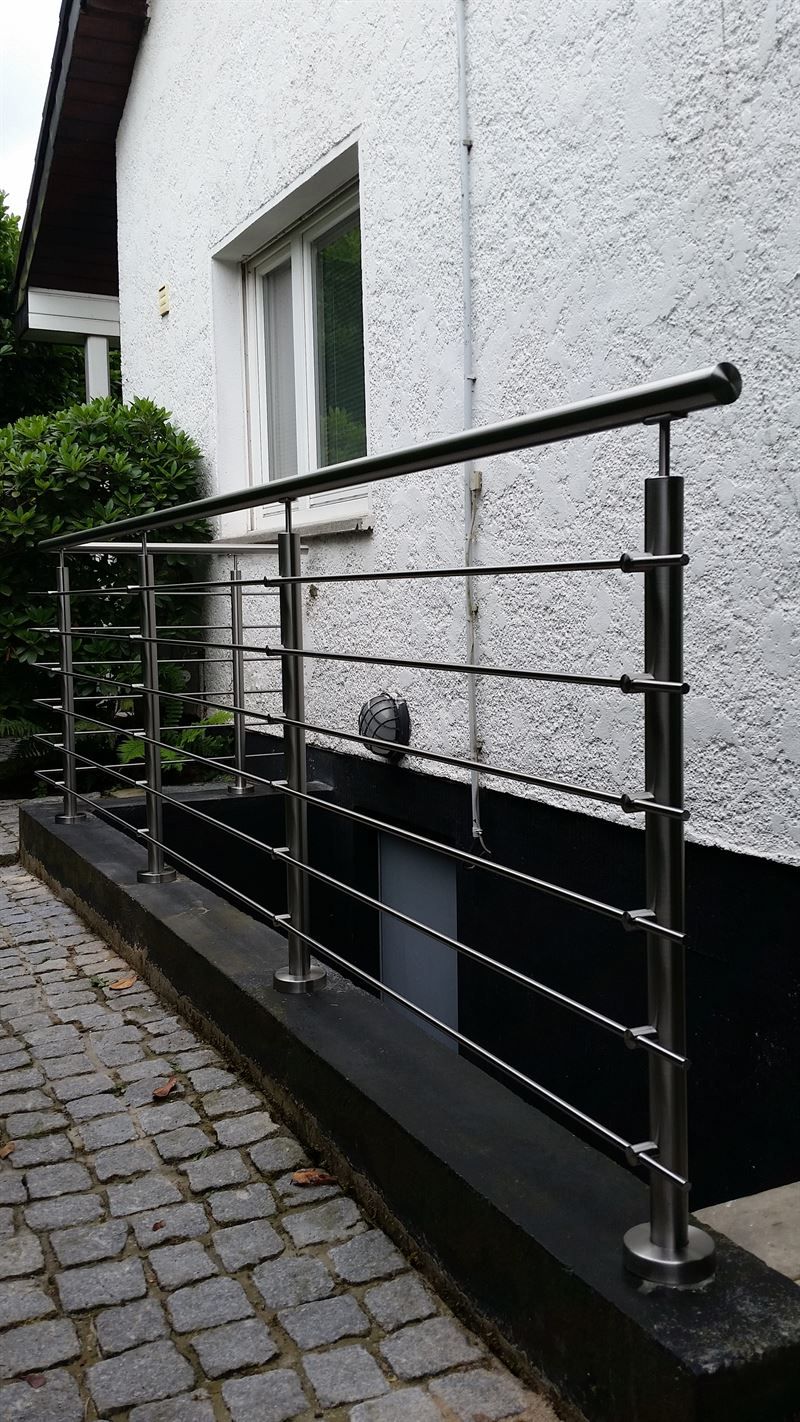 An der Seite eines Hauses ist ein Edelstahlgeländer angebracht.