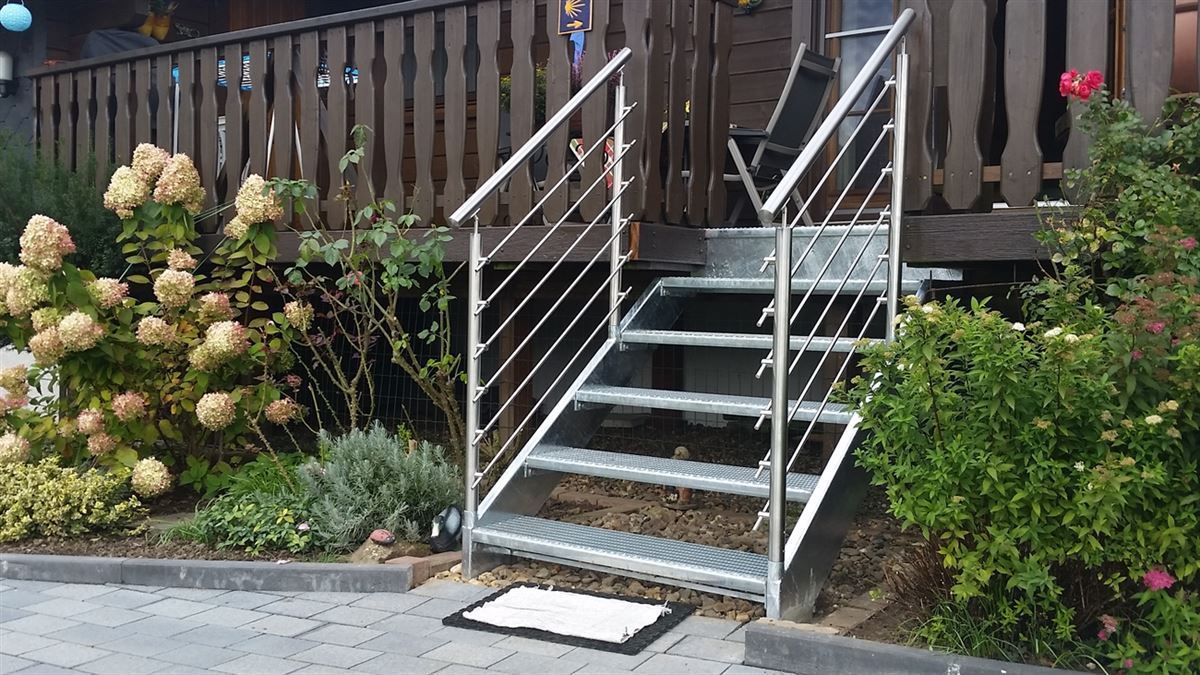 Eine Treppe, die zu einem Haus mit einem Edelstahlgeländer hinaufführt.
