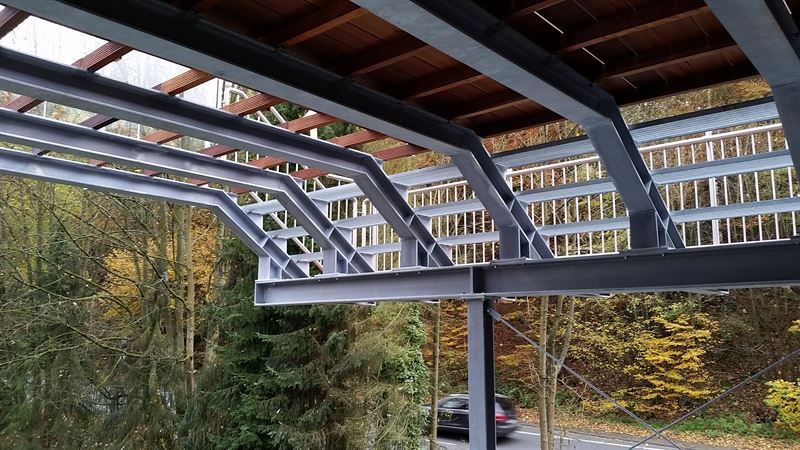 Ein Auto ist unter einer Metallkonstruktion im Wald geparkt.