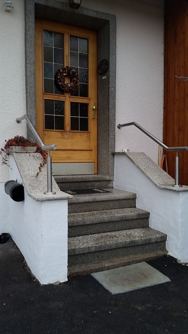 Eine Tür mit einem Kranz darauf und einer Treppe, die dorthin führt