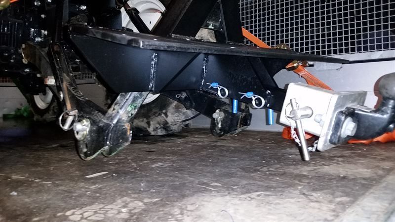 Auf dem Boden steht ein Traktor mit einem daran befestigten Anhänger.