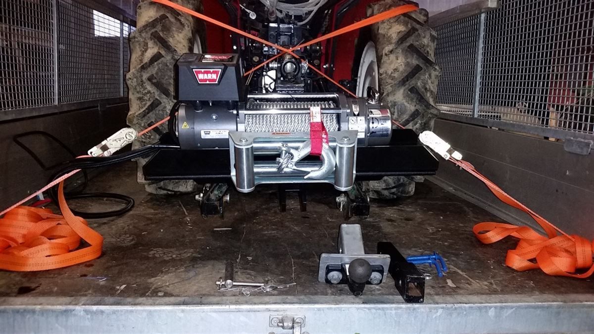 Auf der Ladefläche eines Anhängers steht ein Traktor.