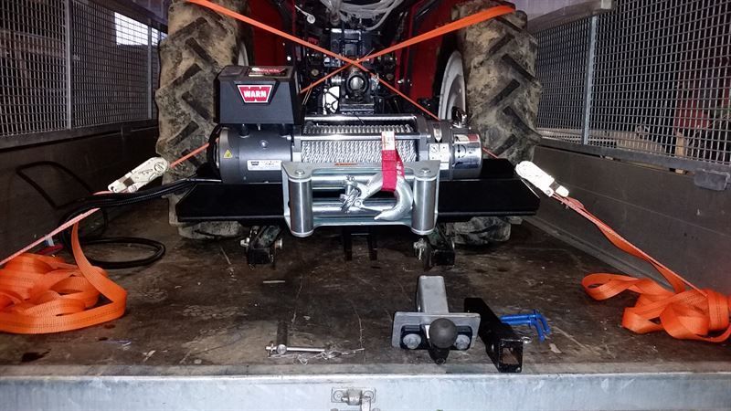 Auf der Ladefläche eines Anhängers steht ein Traktor.