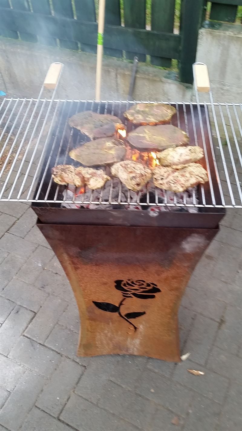 Auf einem Grill mit einer Rose darauf wird Fleisch gegart.