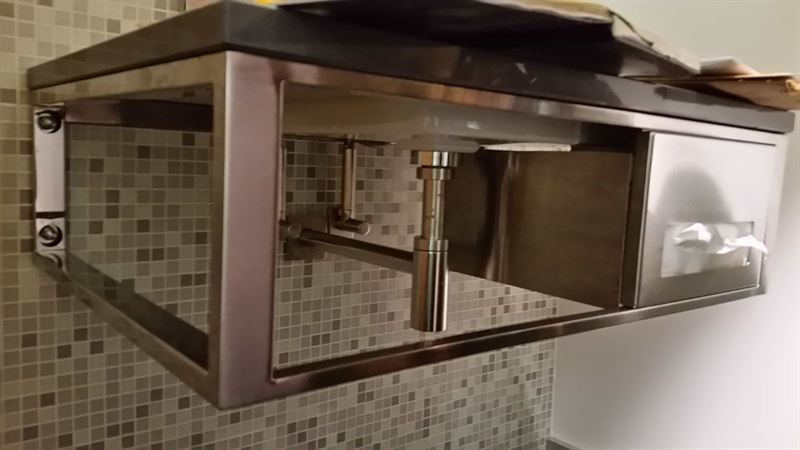 Ein Edelstahlwaschbecken mit schwarzer Arbeitsplatte in einem Badezimmer.