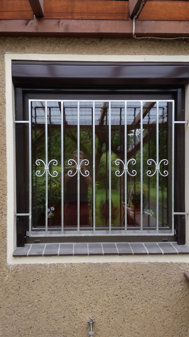 In einer Wand befindet sich ein Fenster mit einem Metallgitter.