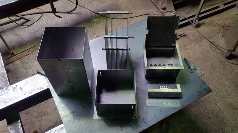 Auf einem Metalltisch stehen drei Metallboxen.