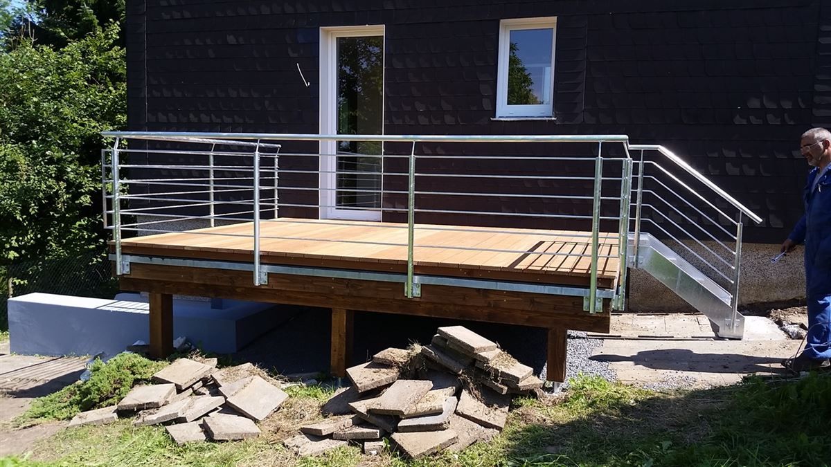 Ein Mann steht vor einem Haus mit Terrasse und Treppe