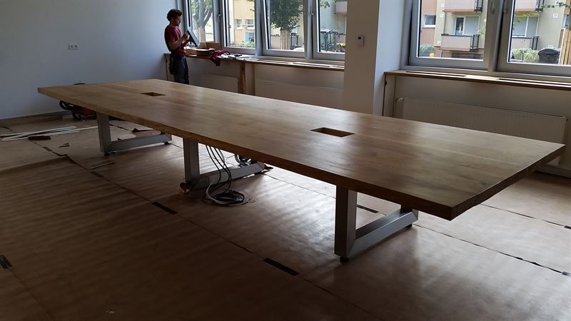 Ein Mann steht neben einem langen Holztisch in einem Raum.