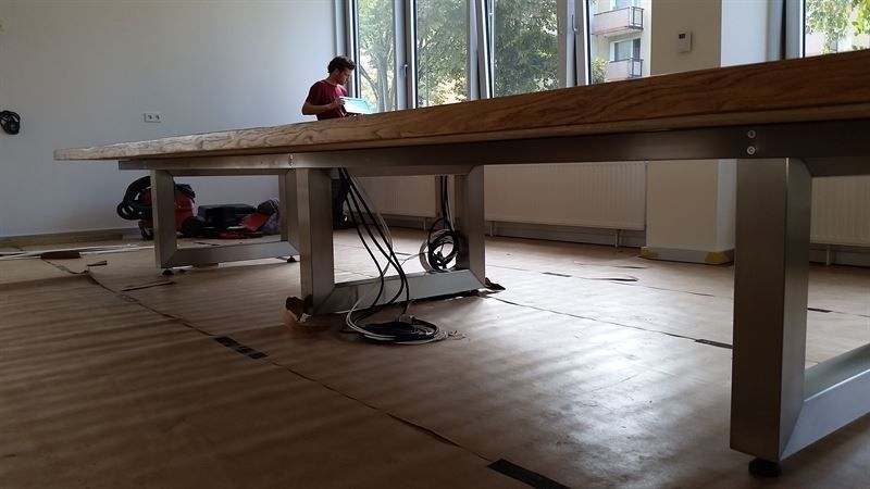 Ein Mann arbeitet in einem Raum an einem Holztisch.