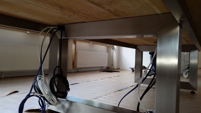 Die Unterseite eines Holztisches, aus dem Drähte herauskommen