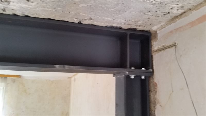 Eine Nahaufnahme eines Metallträgers zwischen zwei Wänden in einem Raum.