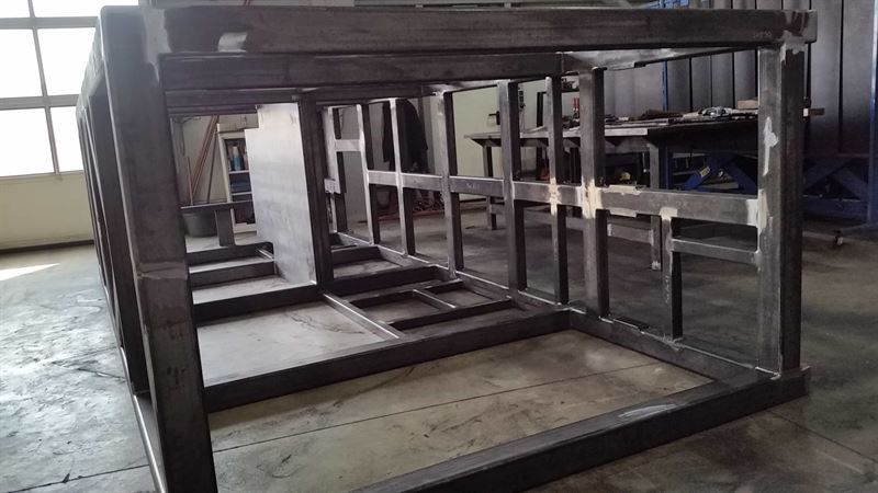 In einem Raum steht ein Metallrahmen auf einem Holzboden.