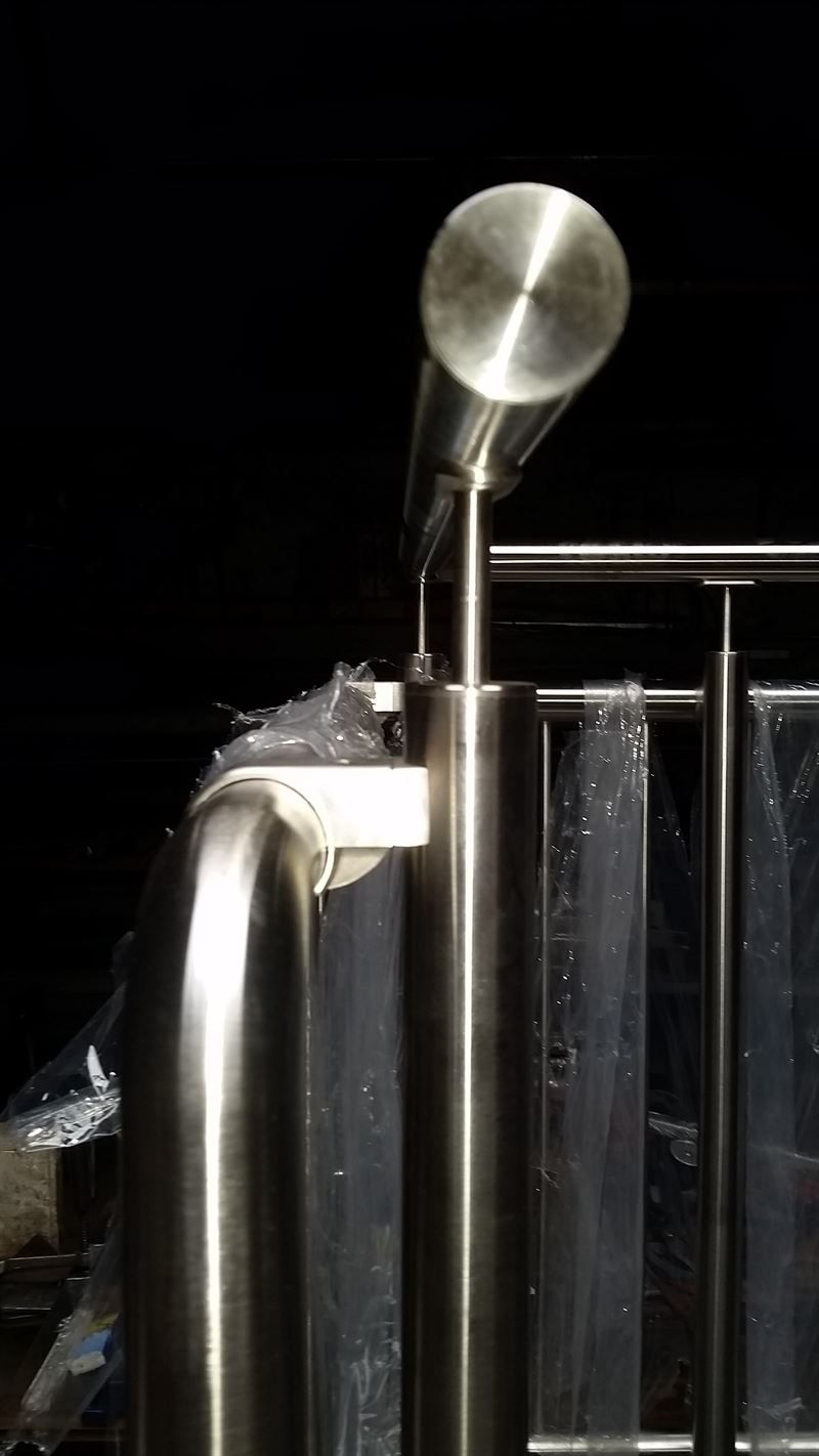 Eine Nahaufnahme eines Edelstahlgeländers vor schwarzem Hintergrund.