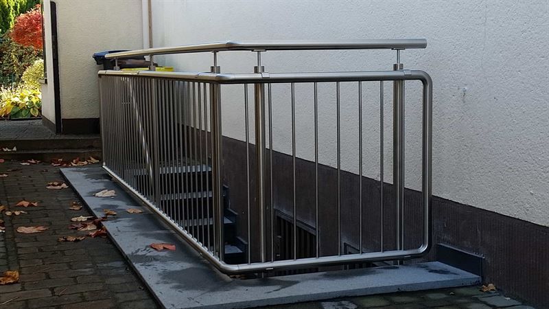 Ein Edelstahlgeländer umgibt eine Treppe, die in den Keller führt.