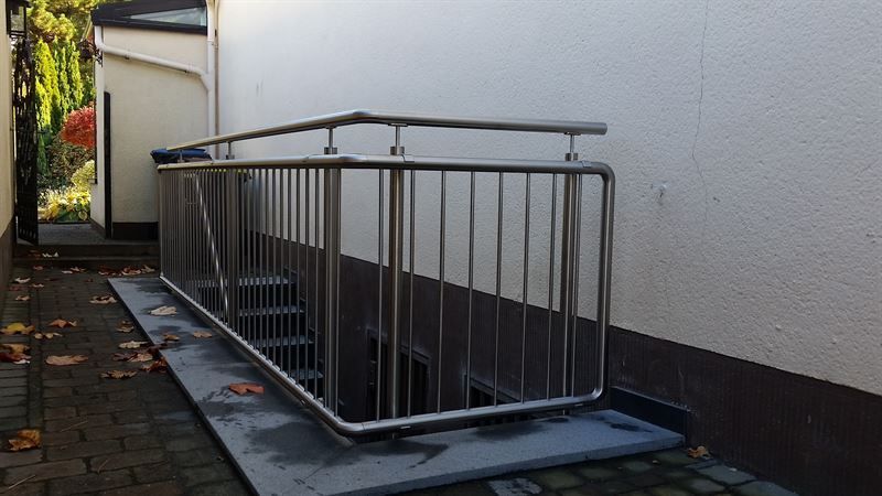 Ein Edelstahlgeländer umgibt eine Treppe, die in den Keller führt.