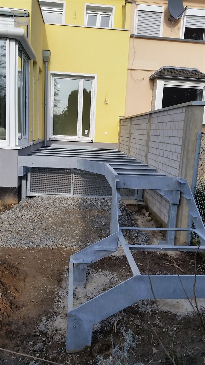 Vor einem gelben Haus wird eine Metalltreppe gebaut.