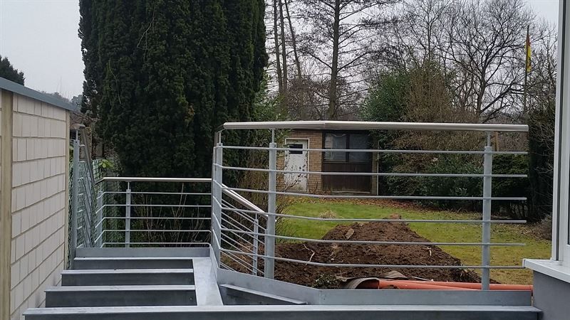 Eine Treppe mit einem Edelstahlgeländer, die zu einem Haus führt.