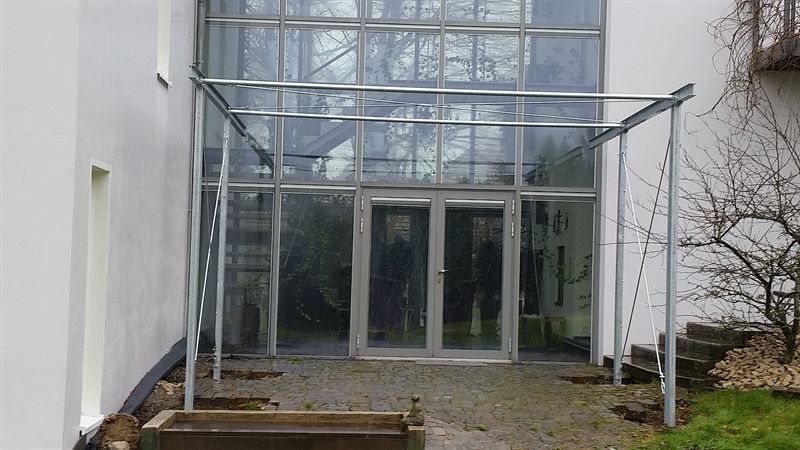 Ein weißes Gebäude mit einer großen Glastür und einer Treppe, die dorthin führt.