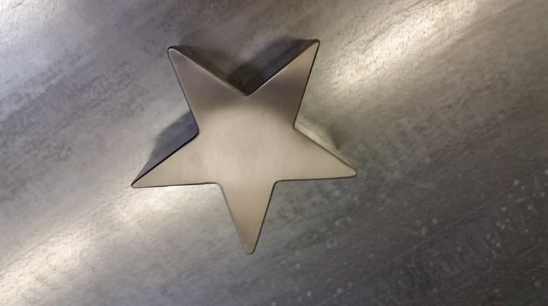 Ein Metallstern sitzt auf einer Metalloberfläche.