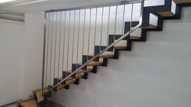 Eine Treppe mit einem Metallgeländer und Holzstufen in einem Raum.