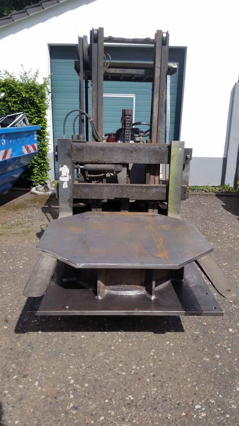 Ein Gabelstapler steht auf einem Parkplatz neben einem Gebäude.